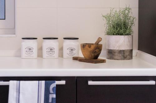 a kitchen counter with three jars and a plant at Blubay Apartments by ST Hotels in Il-Gżira