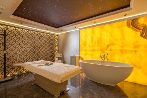 ein Bad mit einer großen Badewanne und einem Bett in der Unterkunft Nobil Luxury Boutique Hotel in Chişinău