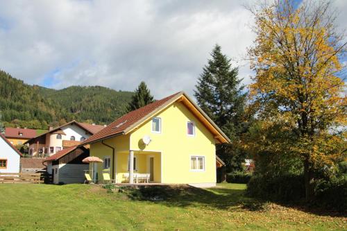 a yellow house with a brown roof on a field at Narrenhaus in Fohnsdorf