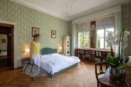 Eine Frau steht in einem Schlafzimmer mit einem Bett in der Unterkunft Villa Brunelli in Riva del Garda