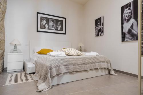 a white bedroom with a bed and pictures on the wall at Sunset Studio in Scicli