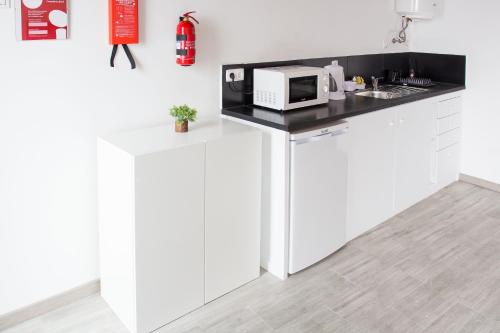 Una cocina con gabinetes blancos y un microondas en una encimera. en Apartamentos Porto de Abrigo, en São Vicente