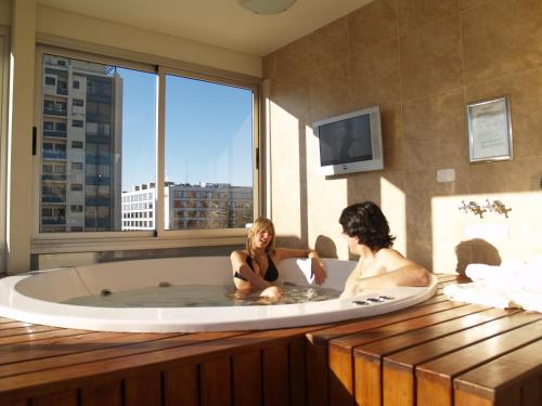 Dos mujeres sentadas en una bañera con ventana en Villaggio Hotel Boutique en Mendoza