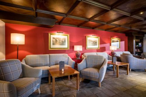 a waiting room with couches and tables and red walls at Sporthotel Austria in Sankt Johann in Tirol