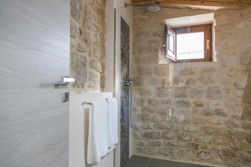 a bathroom with a stone wall and a window at Sunset Studio in Scicli
