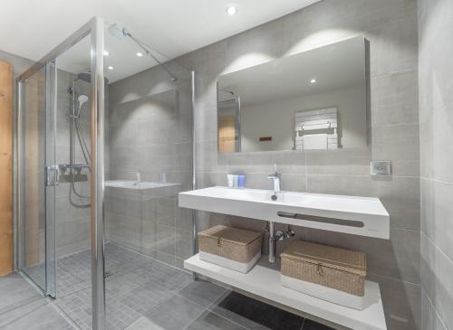 une salle de bain avec un lavabo, une douche et un miroir dans l'établissement Colibri Uno, à Morzine