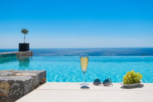 um copo de vinho ao lado de uma taça de uvas e óculos de sol em Alav Pool Villa em Afantou