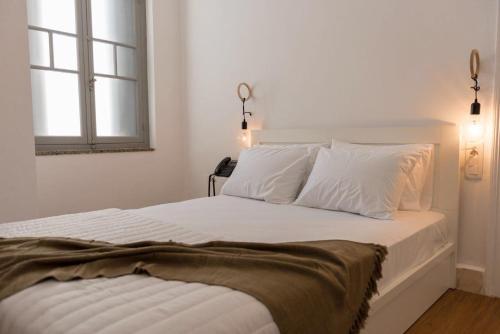 a bedroom with a bed with white sheets and a window at Kumba Hostel in Chania