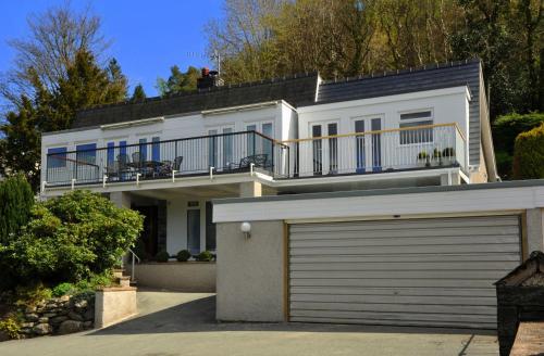 a white house with a balcony and a garage at Maes-y-Garth in Betws-y-coed