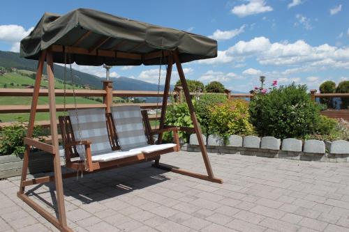 a swing chair with an umbrella on a patio at Pension Wiesenrain in Maranza