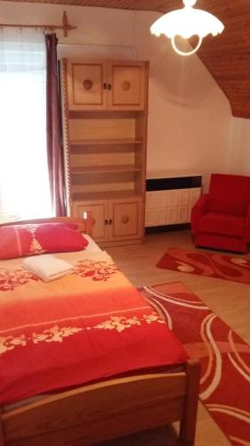 a bedroom with a bed and a red chair at Osho Vendégház in Tiszafüred