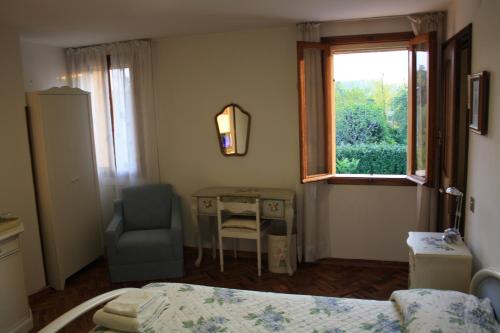 a bedroom with a bed and a desk and a window at B&B Pleris in Asolo