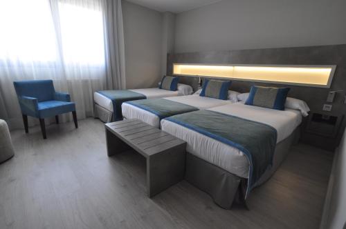 a hotel room with two beds and a chair at Hotel & Spa Real Jaca in Jaca