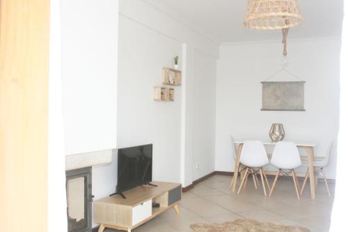 een woonkamer met een televisie en een tafel met stoelen bij Gare Do Sol in Aveiro