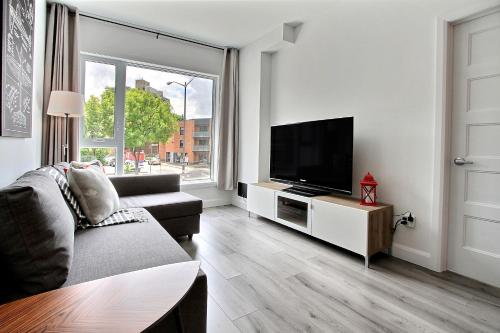 uma sala de estar com um sofá e uma televisão de ecrã plano em INITIAL - PILOTE - Centre-Ville de Québec em Quebeque