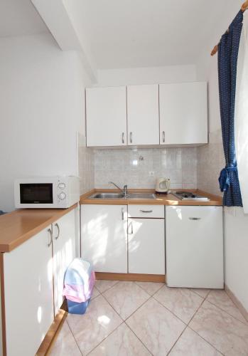 a white kitchen with white cabinets and a sink at Apartments IVO in Tučepi