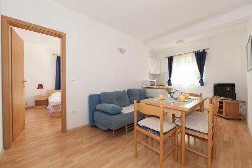 a living room with a table and a blue couch at Apartments IVO in Tučepi