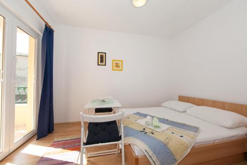 a small bedroom with a bed and a chair at Apartments IVO in Tučepi