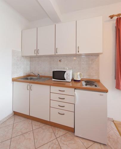 a kitchen with white cabinets and a microwave at Apartments IVO in Tučepi