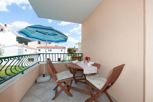 a balcony with a table and chairs and an umbrella at Apartments IVO in Tučepi
