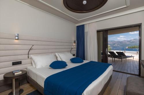 sypialnia z łóżkiem z niebieskimi poduszkami i balkonem w obiekcie RMH Lazure Luxury Apartments w mieście Lopud