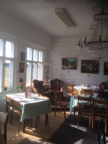 a dining room with tables and chairs and a chandelier at Kansakoulu in Västanfjärd