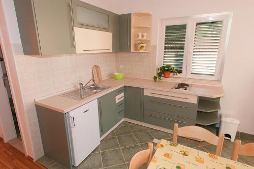 a small kitchen with green cabinets and a sink at Apartments IVO in Tučepi