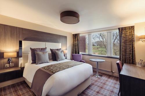 ein Hotelzimmer mit einem großen Bett und einem Schreibtisch in der Unterkunft Abbey House Hotel in Barrow in Furness