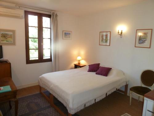 a bedroom with a bed with two purple pillows on it at La Maison de Velours in Villeneuve-sur-Lot