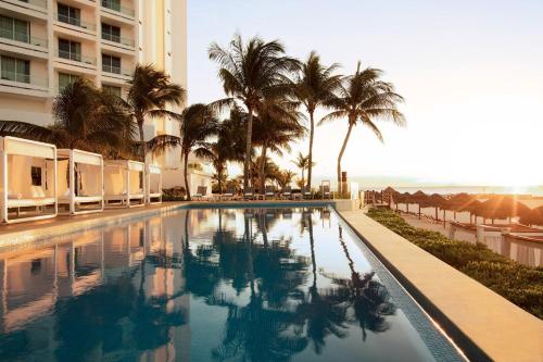 a swimming pool with palm trees and a building at Krystal Grand Cancun All Inclusive in Cancún