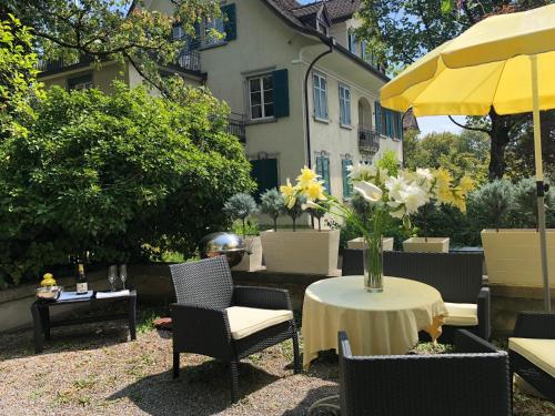 een patio met een tafel en een vaas met bloemen erop bij Garden Studio Apartment Zürichberg in Zürich