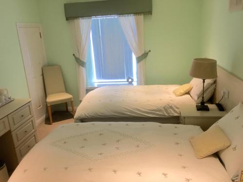 a bedroom with two beds and a window at Shawlee Cottage in Airdrie
