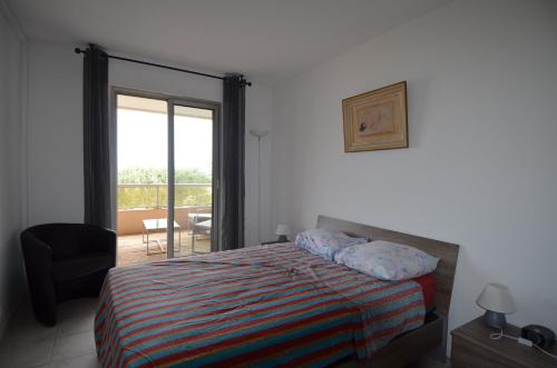 ニースにあるAppartement 5 personnes avec piscine sur la Corniche Fleurie à Niceのベッドルーム1室(ベッド1台付)、バルコニーへのドアが備わります。