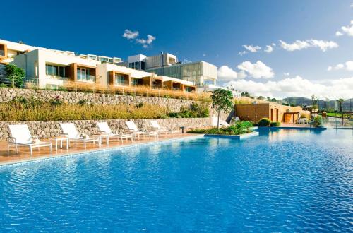 a swimming pool with lounge chairs in a resort at Palmalife Bodrum Resort & Spa in Yalıkavak
