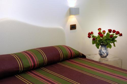 a vase of flowers sitting on a table next to a bed at Poggio dei Gorleri in Diano Marina