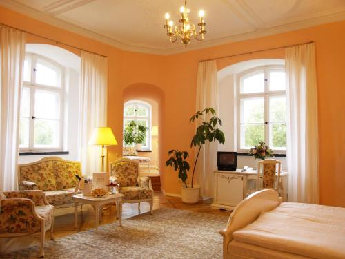 a living room with orange walls and a bed and chairs at Hotel Schloss Spyker in Glowe