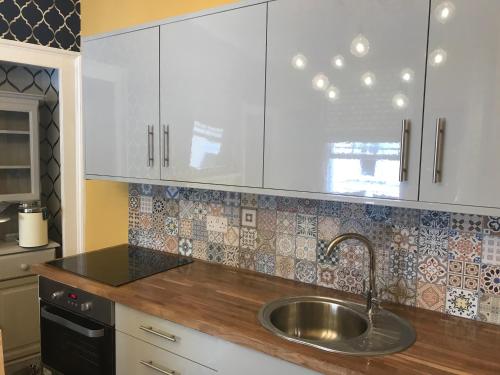 cocina con fregadero y armarios blancos en Central city pad one bedroom plus double sofabed en Bath