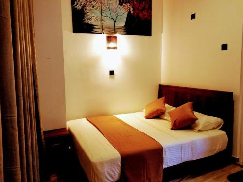 a bedroom with a bed with orange and white sheets at Queens mount in Kandy