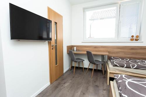 a room with a desk with two chairs and a television at Pohoda Ubytovanie Stupava in Stupava