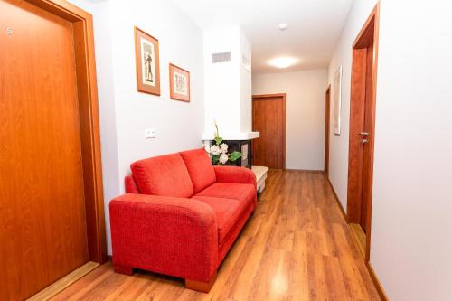 a living room with a red chair and wooden floors at Pohoda Ubytovanie Stupava in Stupava