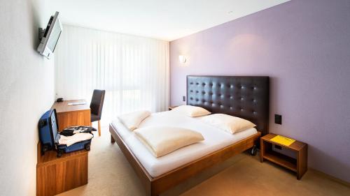 a bedroom with a large bed and a television at Swiss Heidi Hotel in Maienfeld