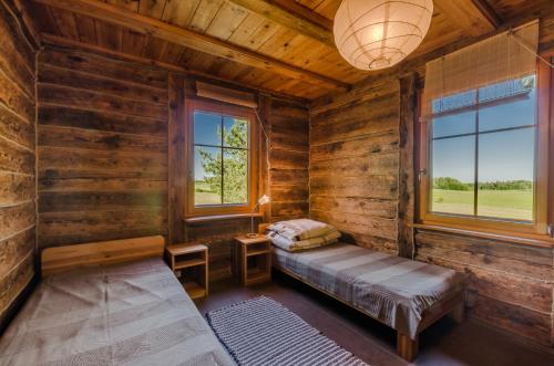 a bedroom in a log cabin with a bed and two windows at Domek na Górce in Sorkwity