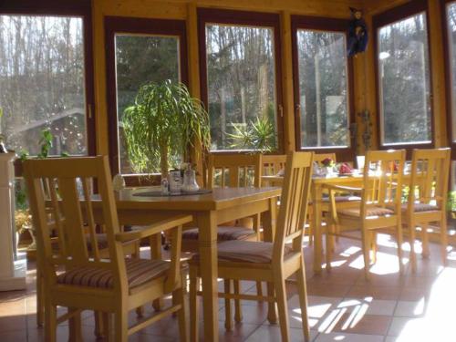uma sala de jantar com mesa, cadeiras e janelas em Pension Haus am Heubach em Bad Staffelstein