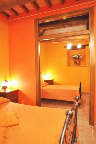 a bedroom with orange walls and a bed and a mirror at Agriturismo Arcobaleno della Torretta in Giano dellʼUmbria