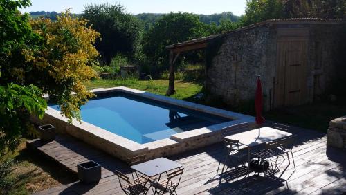 a swimming pool in a yard with a table and chairs at Le clos des abeilles in Ruch