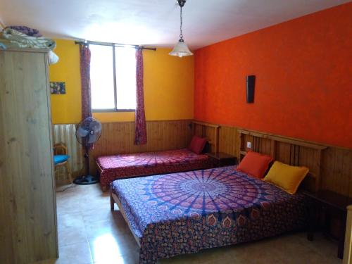 1 Schlafzimmer mit 2 Betten und orangefarbenen Wänden in der Unterkunft Casa Rural Las Gesillas in Arenas de San Pedro
