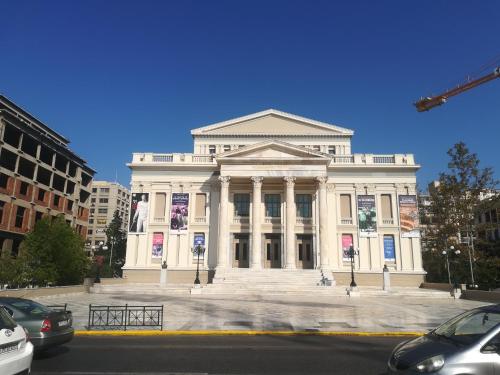 a large white building on a city street with cars at Port's little gem in Piraeus