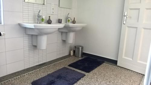 a bathroom with two sinks and blue rugs at Vila Adelaide in Brtníky
