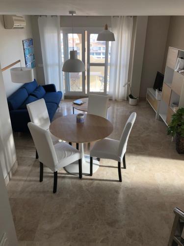 a living room with a table and chairs and a blue couch at Puerto Fino Apartamentos in Almerimar