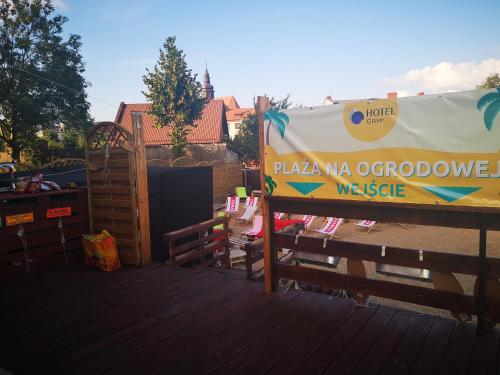 a sign on a deck next to a wooden fence at Hotel Gryf in Kościerzyna